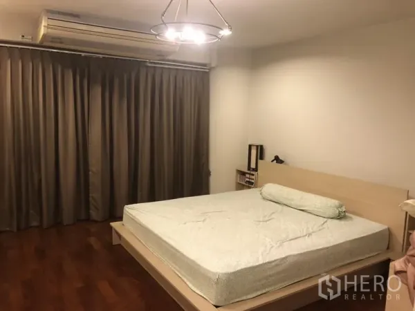 Condominium for rent in Bang Rak, Bangkok - Spacious bedroom with large bed, chandelier light, long curtains and polished wood flooring.