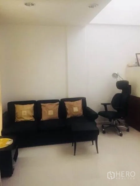 Townhouse for rent in Bang Kapi, Bangkok - Compact living area with black sofa, cushions and office chair.