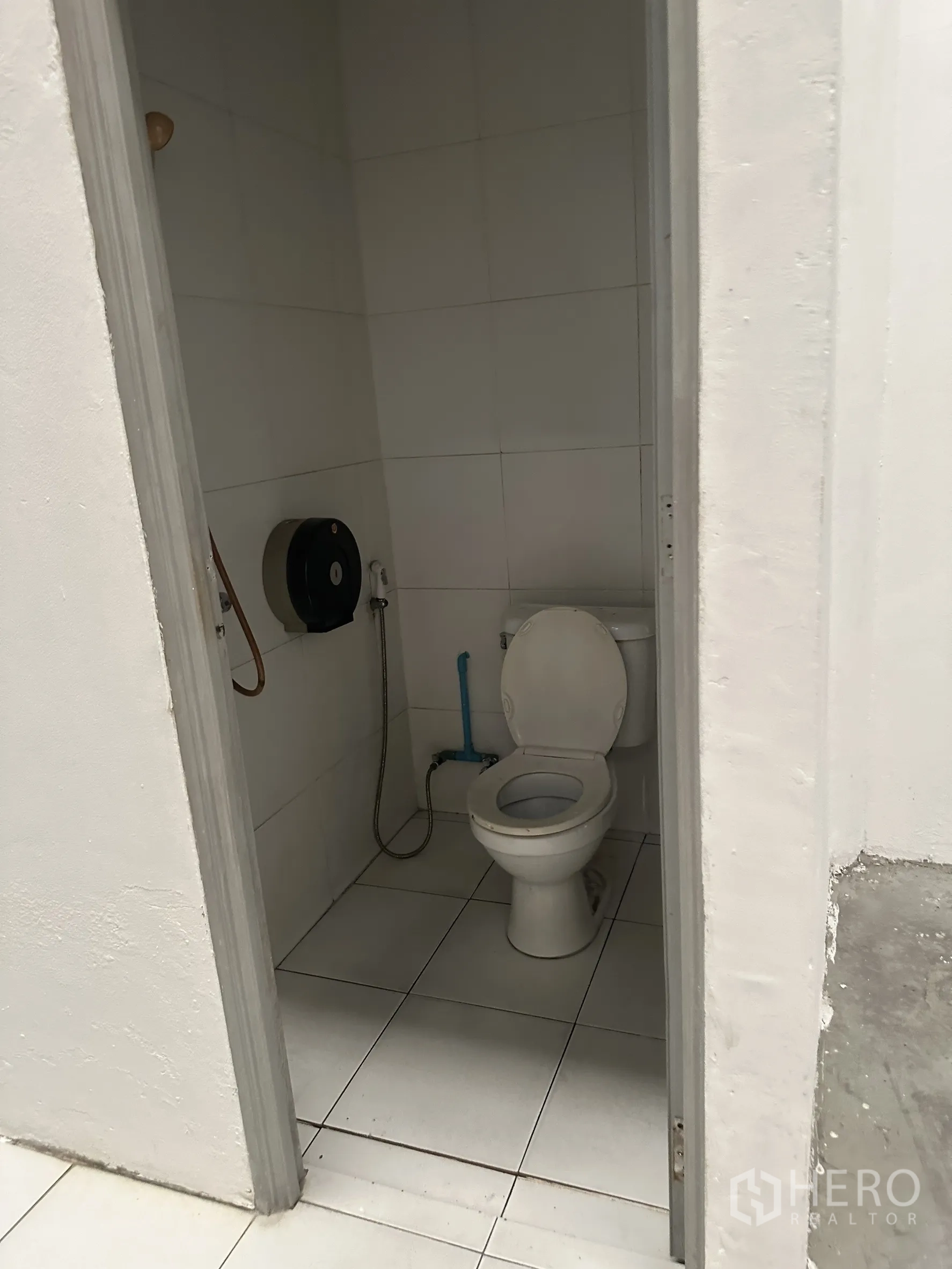 Factory for rent in Khlong Luang, Pathum Thani - Clean tiled restroom with western toilet and handheld bidet inside the factory.