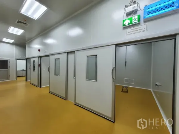 工厂 出售在Lam Luk Ka, Pathum Thani - 洁净区走廊，多个推拉门房间与应急出口指示。