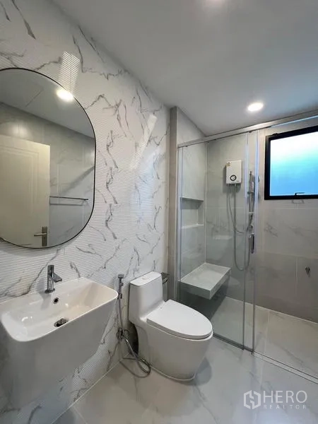 Detached House for rent or sale in Saphan Sung, Bangkok - Clean bathroom with round mirror, toilet and glass shower cubicle.