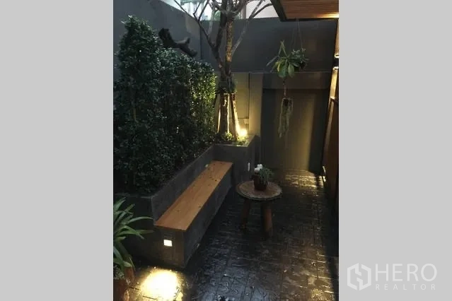 Detached House for rent in Watthana, Bangkok - Courtyard with planter wall, bench seating and warm evening lighting.