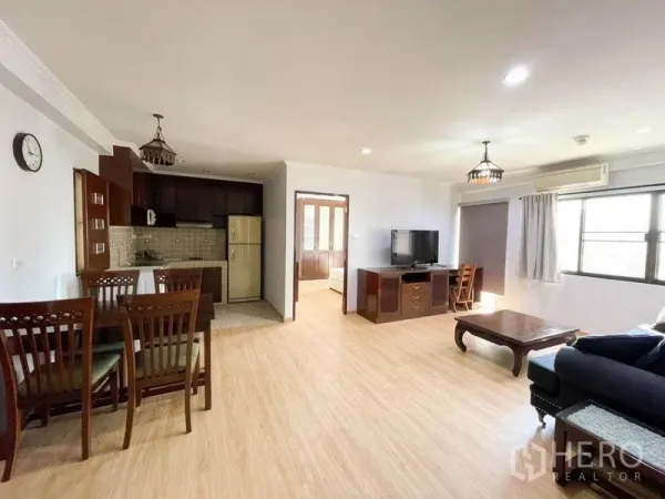 Condominium for rent or sale in Khlong Toei, Bangkok - Open-plan living and dining area with kitchen, wood flooring and natural light.