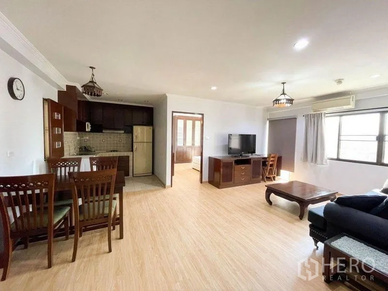 Condominium for rent or sale in Khlong Toei, Bangkok - Open-plan living and dining area with kitchen, wood flooring and natural light.