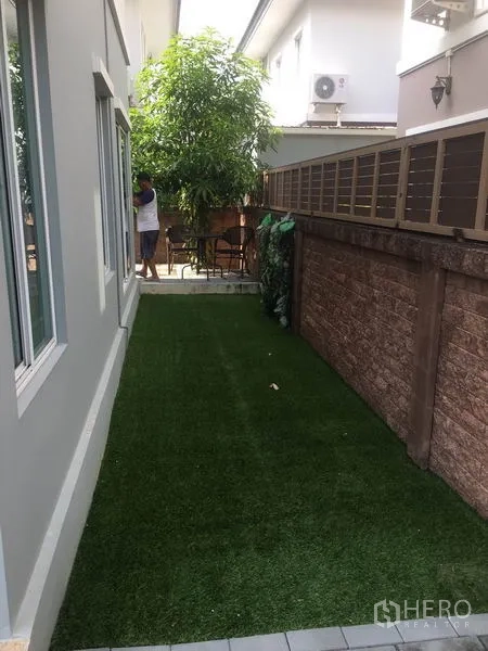 Detached House for rent in Suan Luang, Bangkok - Narrow lawn along the house with brick privacy wall and greenery.