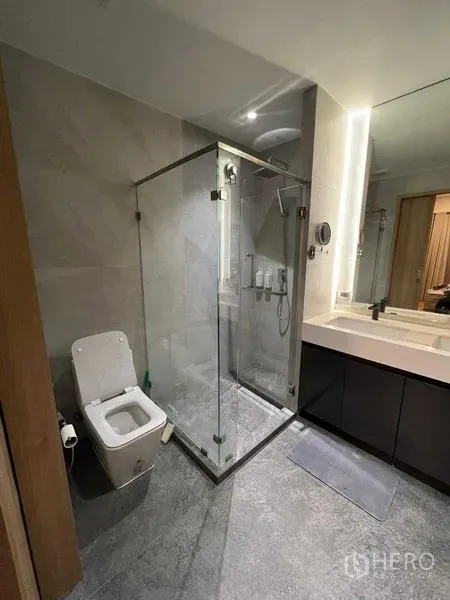 公寓 出租或出售在Phaya Thai, Bangkok - 灰色石材地面浴室，玻璃淋浴房与坐便器。