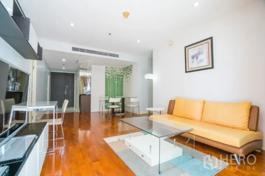 Condominium for rent or sale in Khlong Toei, Bangkok - Living room toward the entry with glass coffee table and media wall.