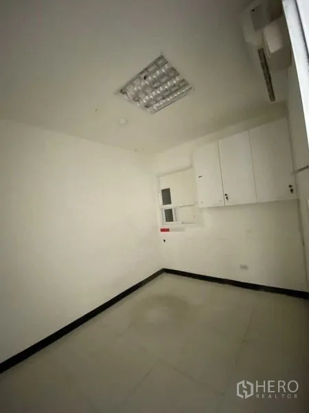Retail Space for rent - Small back office with white cabinets, window and tiled flooring.