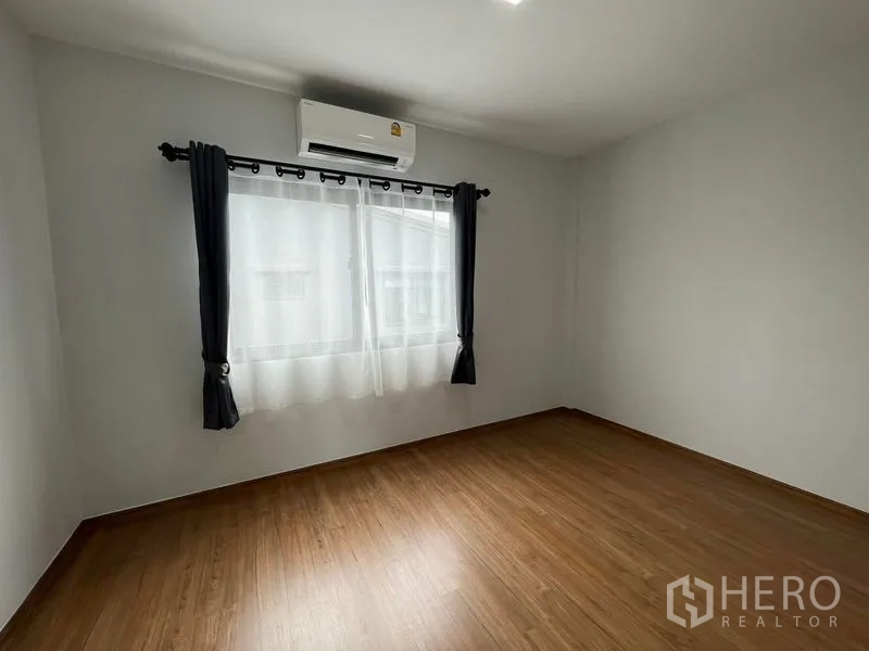 Townhouse for rent - Empty spare bedroom with wooden floor, curtained window and air conditioner.