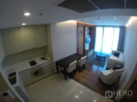 Condominium for rent in Khlong Toei, Bangkok - Open-plan living and dining area next to the kitchen, with sofa, dining table, and large window.