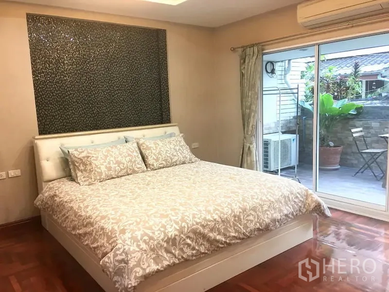 联排别墅 出租在Bang Rak, Bangkok - 主卧配特大床，推拉玻璃门通向露台，空调与木地板。