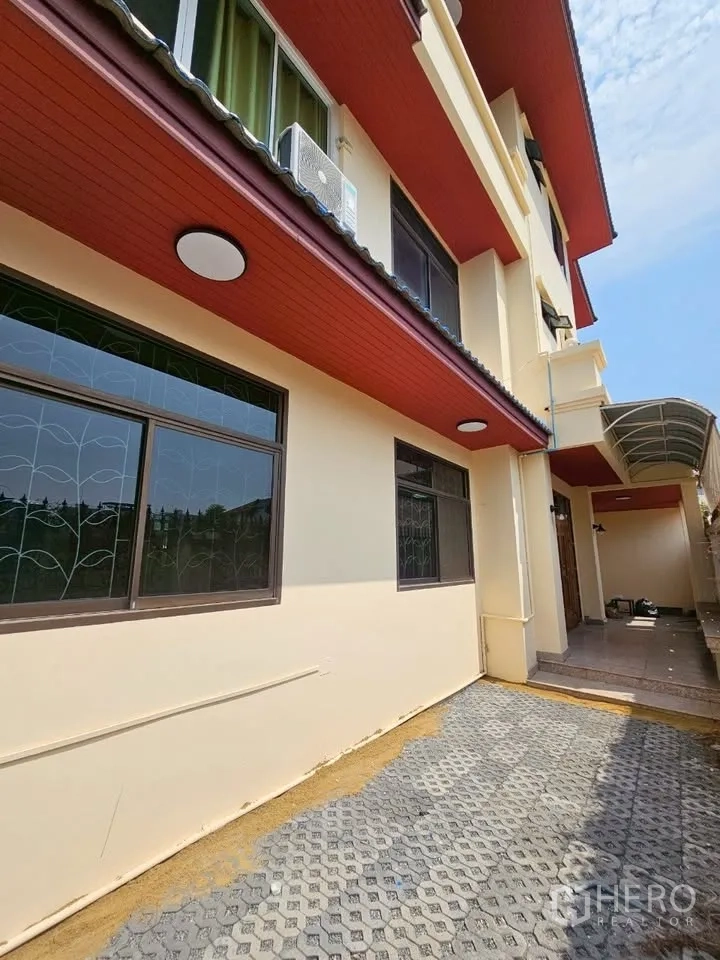 带办公室的家 for rent in Wang Thonglang, Bangkok - 建筑外侧奶油色外墙，红色檐口，带防护栏窗与铺装院道。