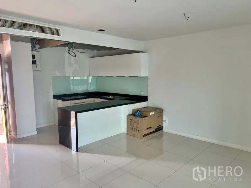 Condominium for rent in Bang Kho Laem, Bangkok - Modern open-plan kitchen with black countertops, glass backsplash, and white cabinetry.