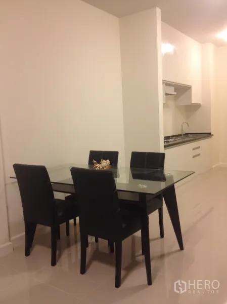 联排别墅 出租在Watthana, Bangkok - 四人玻璃餐桌，毗邻紧凑型茶水厨房。