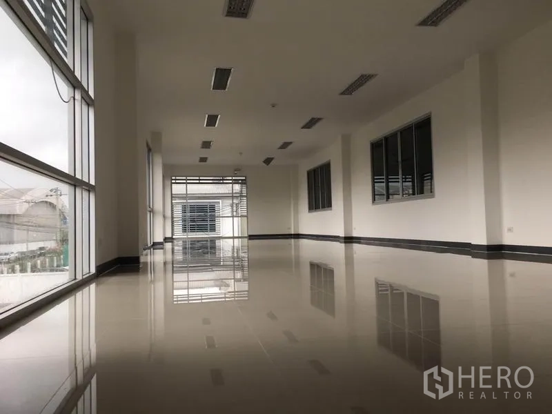Factory for rent in Samut Prakan - Second-floor office area with floor-to-ceiling windows, glossy floor and fluorescent lighting.