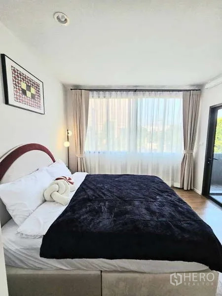 Townhouse for rent in Suan Luang, Bangkok - Sunlit bedroom with double bed, wide window and door to a small balcony.