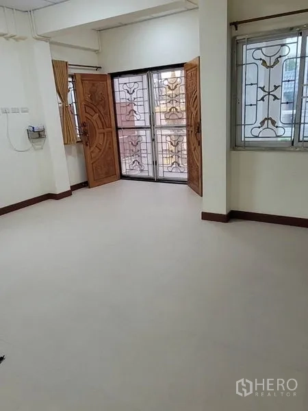 Detached House for rent in Khlong Toei, Bangkok - Ground-floor room with double wooden doors, security screens and clean tiled flooring.