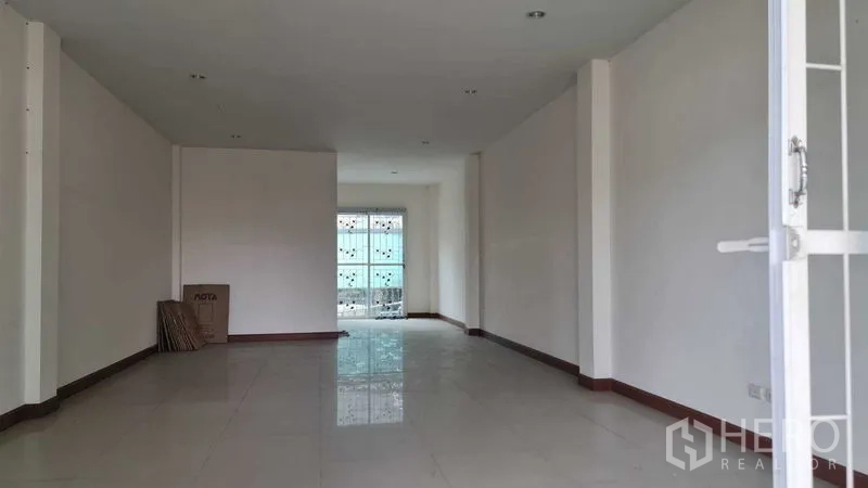 Townhouse for  in Lam Luk Ka, Pathum Thani - Long open-plan living area with tiled floors and rear glass door.