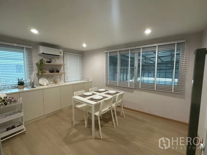 Warehouse for sale in Pathum Thani - Pantry and dining space with a white table, built-in cabinets and window blinds in the office building.