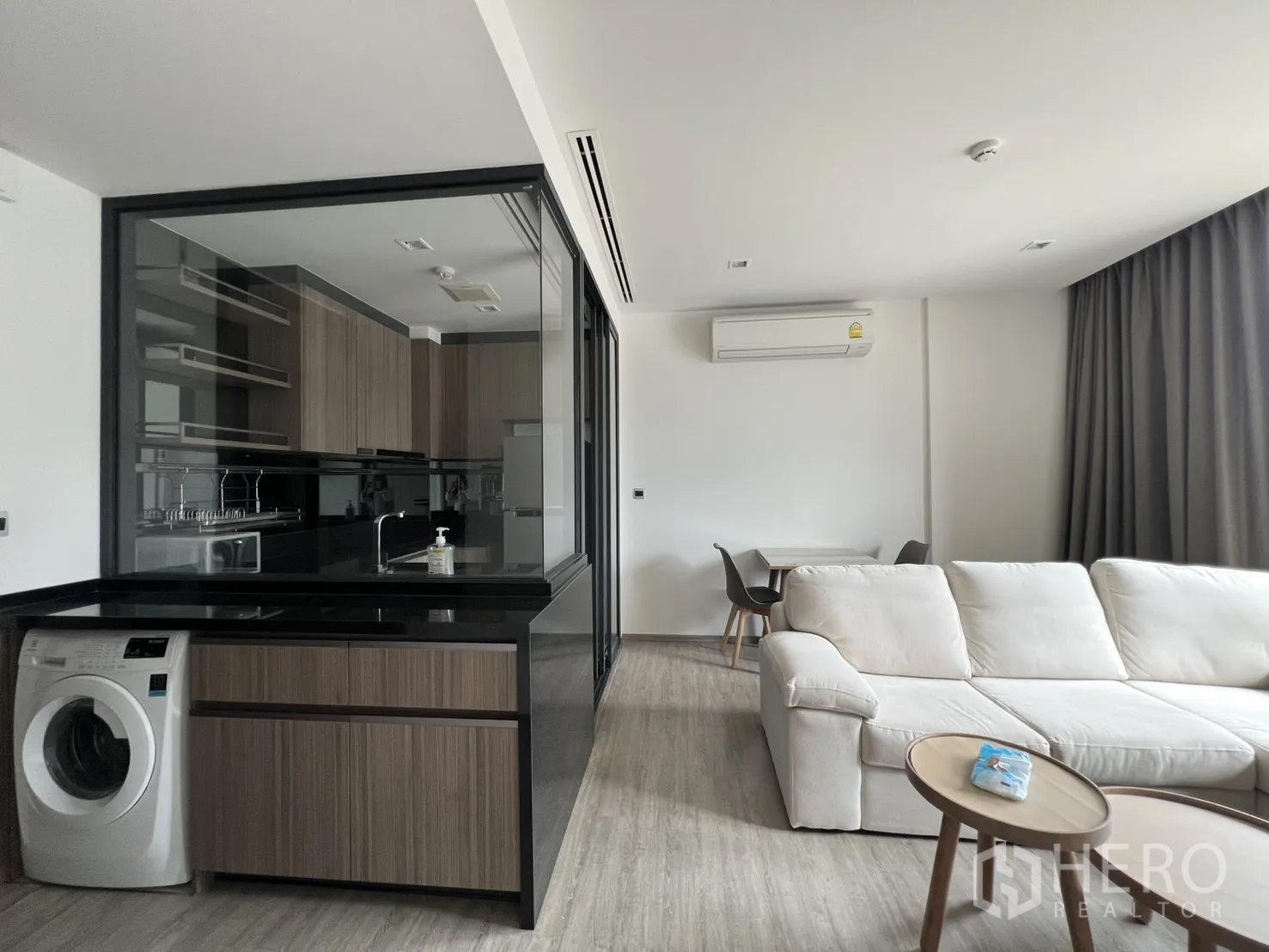 คอนโด for rent in Watthana, Bangkok - มุมนั่งพักผ่อนกว้างข้างครัวผนังกระจกและมุมรับประทานอาหารขนาดกะทัดรัดใต้แอร์.