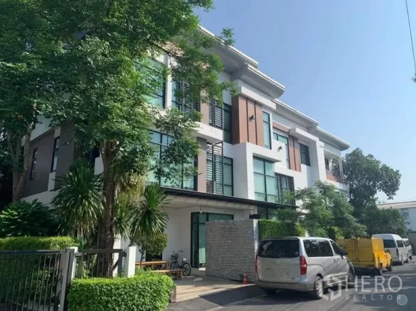 带办公室的家 出售在Wang Thonglang, Bangkok - 现代住办合一建筑转角外观，绿荫环绕并设停车位