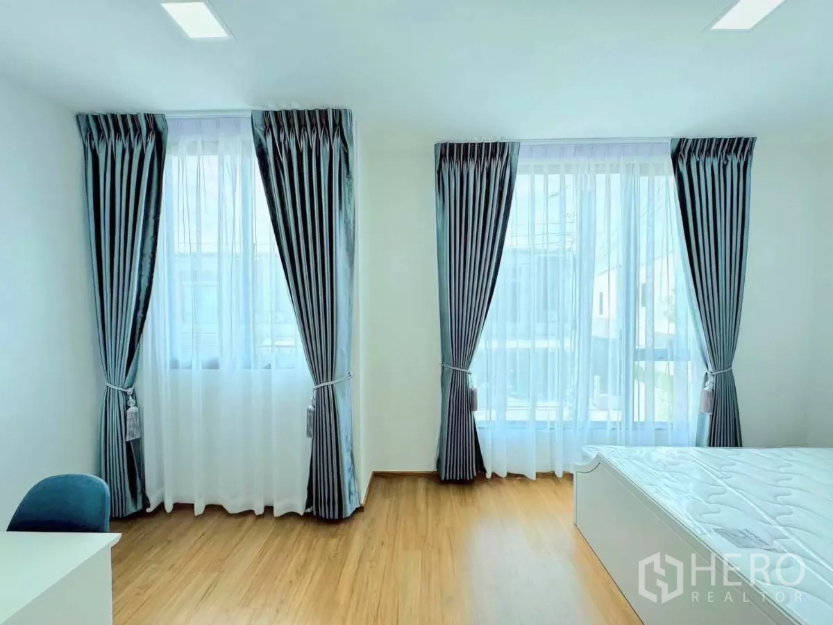 ทาวน์เฮาส์ ให้เช่าในBang Phli, Samut Prakan - ห้องนอนกว้าง มีหน้าต่างสองด้าน ผ้าม่านสองชั้น โต๊ะทำงาน และเตียงบนพื้นลามิเนต