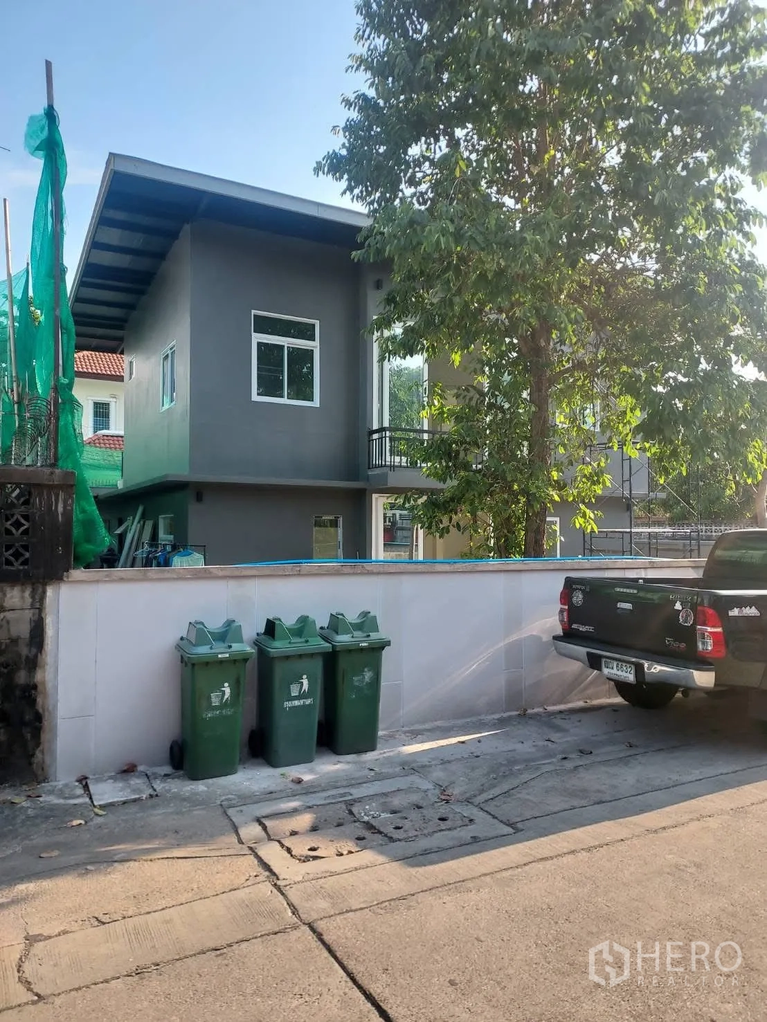 บ้านเดี่ยว for rent in Watthana, Bangkok - มุมมองหน้าบ้านจากถนน มีรั้วเตี้ยและต้นไม้ขนาดใหญ่.