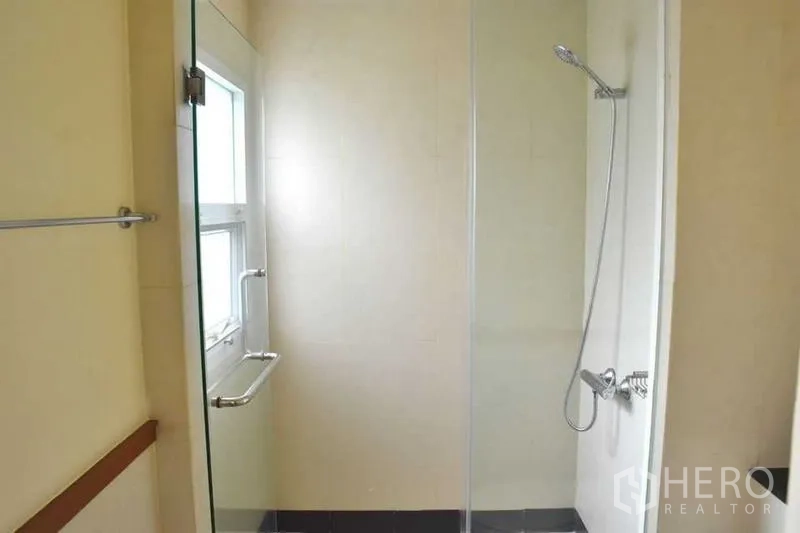 Apartment for rent in Sathon, Bangkok - Bathroom with glass‑enclosed shower and a window for natural light.