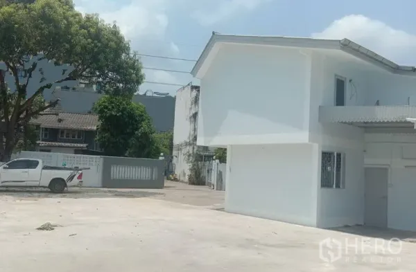 Home Office for rent in Khlong Toei, Bangkok - Spacious open forecourt and entrance gate beside the white two-storey building, suitable for multiple cars.