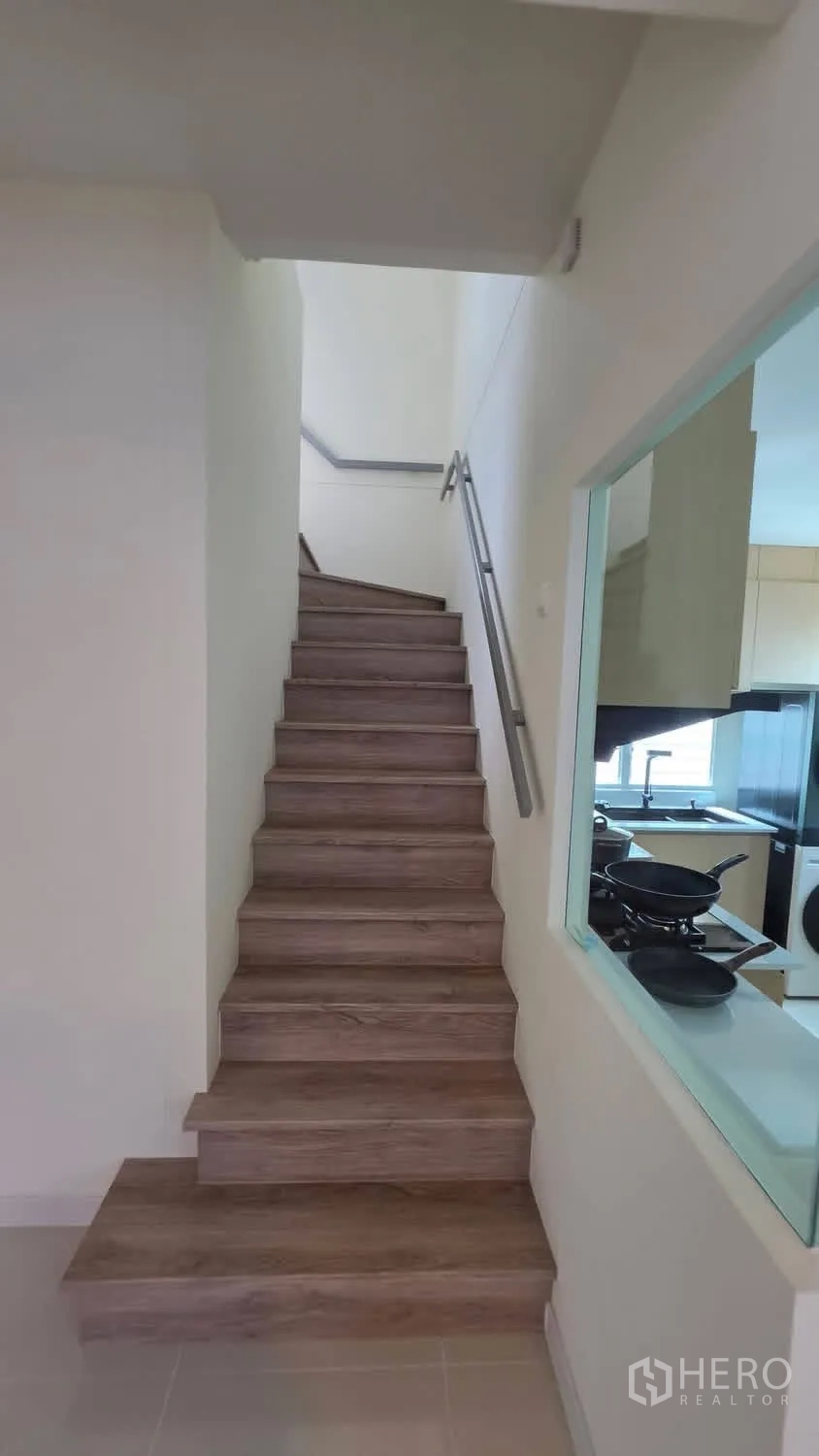 独栋房屋 for rent in Bang Phli, Samut Prakan - 带扶手的木质楼梯，旁边为厨房。