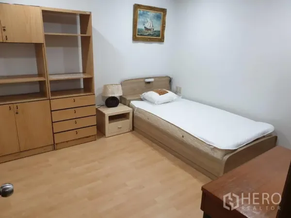 Condominium for rent in Watthana, Bangkok - Second bedroom with a single bed, built-in shelves and drawers, and wood flooring.