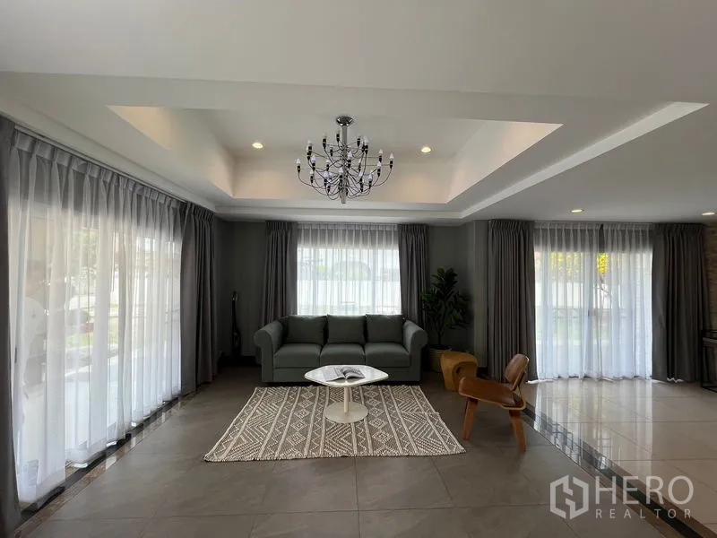 独立式住宅 出售在Mueang Pathum Thani, Pathum Thani - 正式客厅，层次天花与吊灯，三面纱帘与沙发。