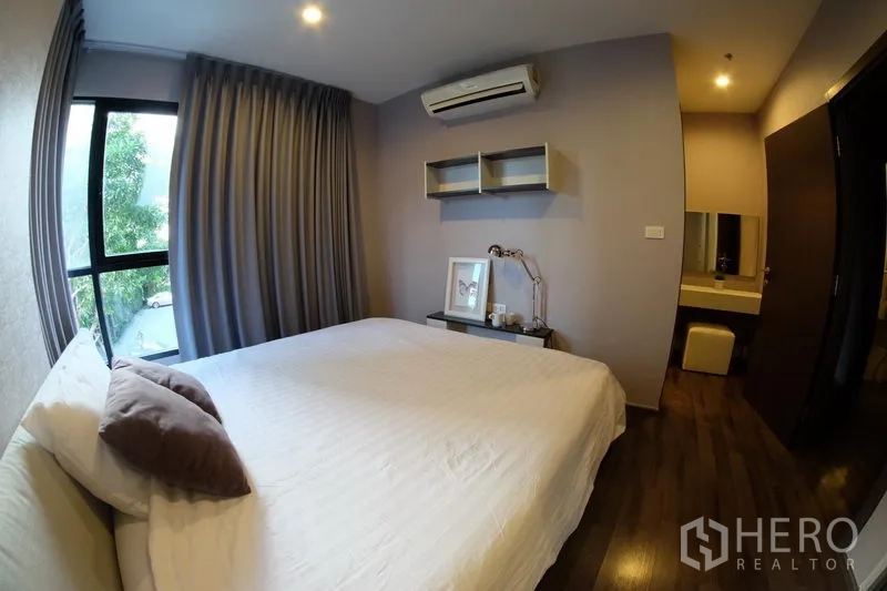 公寓 出租在Watthana, Bangkok - 主卧配壁挂收纳与梳妆区，空调齐全，窗外可见树景。