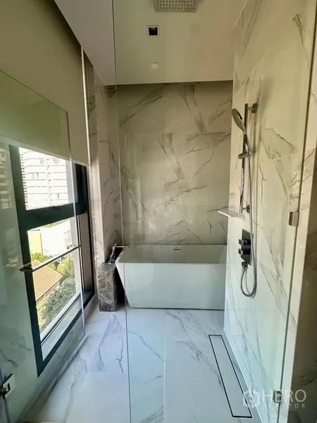 Condominium for rent - Luxury bathroom with freestanding tub, rain shower and marble tiles by the window.
