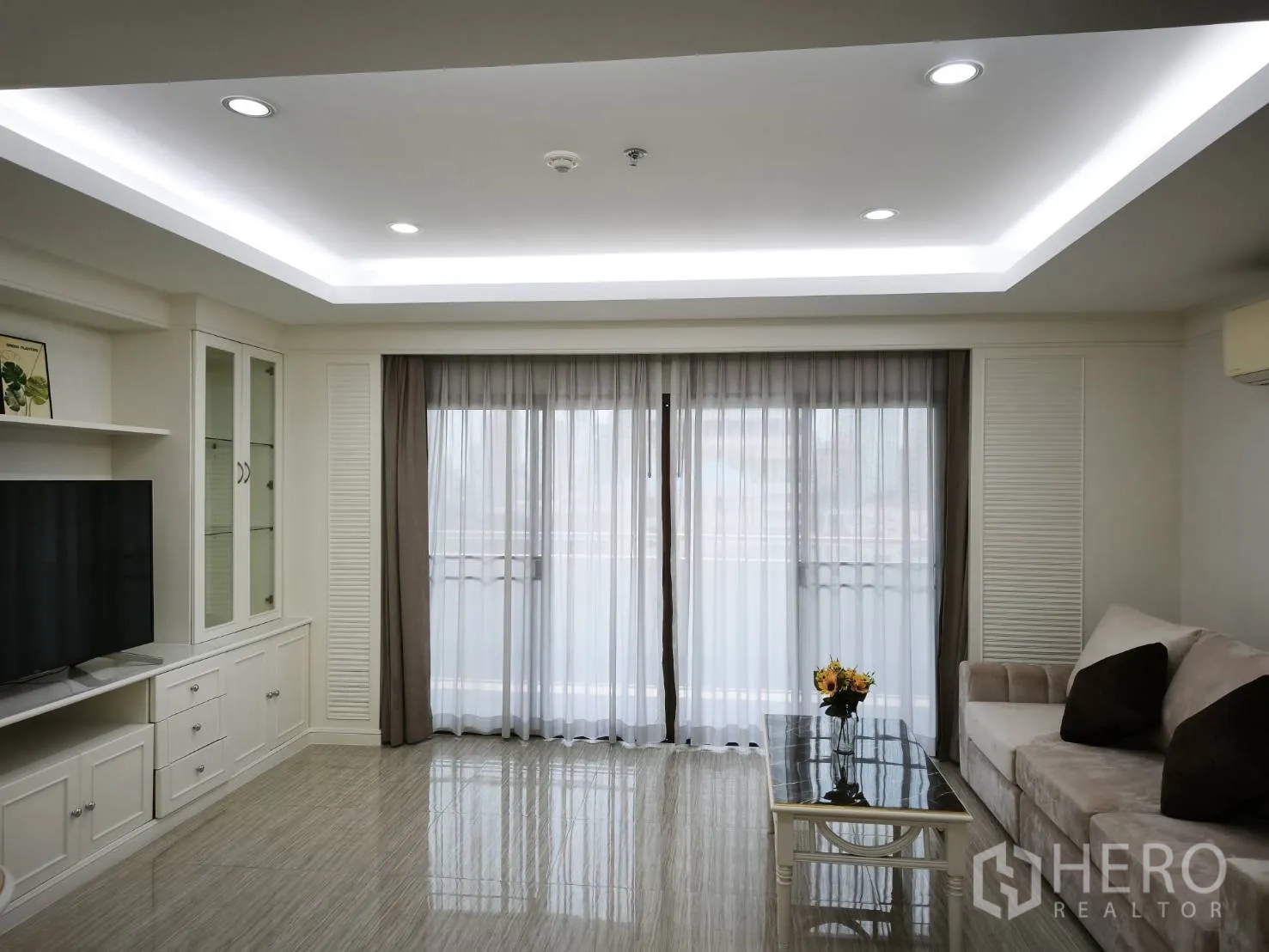 คอนโด for rent in Watthana, Bangkok - ห้องนั่งเล่นมีตู้ทีวีบิลท์อิน โซฟา ไฟฝังฝ้า และผ้าม่านโปร่งที่ประตูระเบียง