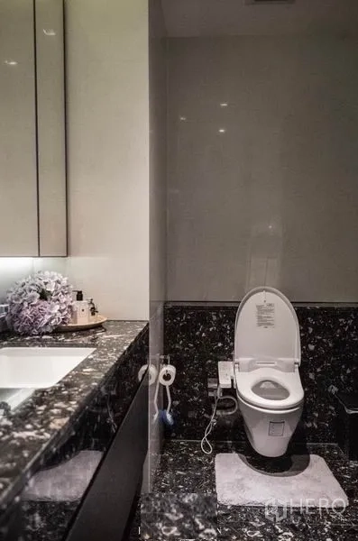Condominium for rent in Khlong Toei, Bangkok - Contemporary bathroom with black marble vanity and modern toilet.