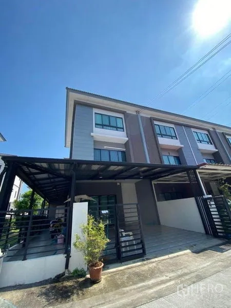 Townhouse for sale in Wang Thonglang, Bangkok - Modern three-storey townhouse exterior with covered double carport, front gate and wide windows.
