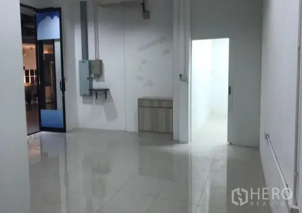 办公空间 出租在Watthana, Bangkok - 白色办公内部，亮面瓷砖地、配电箱以及通往后室的门。