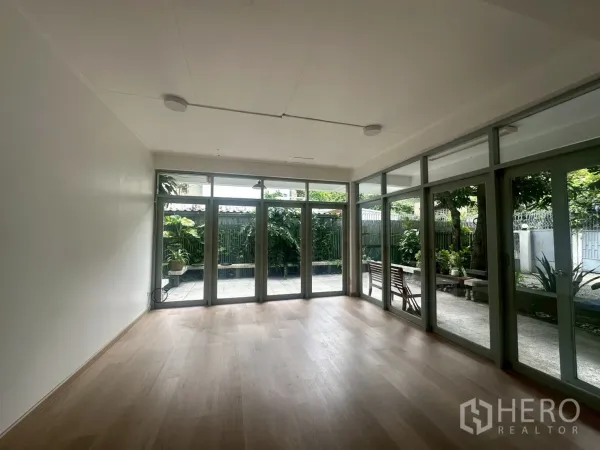 独立式住宅 出租在Watthana, Bangkok - 明亮客厅，浅色木地板，整面落地玻璃门通向露台。