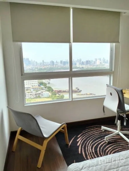 公寓 出售在Yan Nawa, Bangkok - 大窗旁的书桌与休闲椅，可观河景与城市天际线