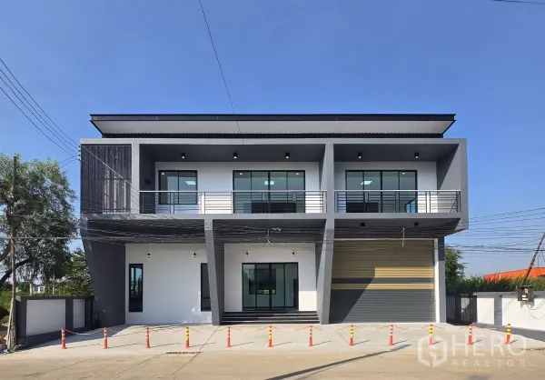 货栈 出售在Lam Luk Ka, Pathum Thani - 现代两层办公室立面与仓库，设阳台、宽幅卷闸门和混凝土装卸区。