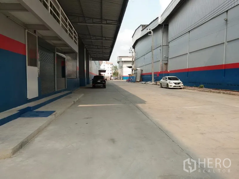 货栈 出租在Bang Phli, Samut Prakan - 仓库外侧带雨棚的装卸区与车道，卡车转弯与停靠空间充足