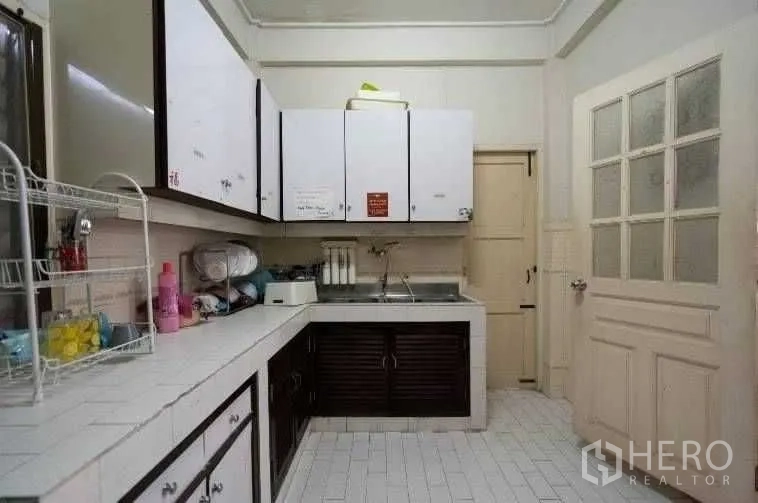 Detached House for rent in Khlong Toei, Bangkok - Functional kitchen with white tiled countertops, upper cabinets, and a stainless-steel sink.