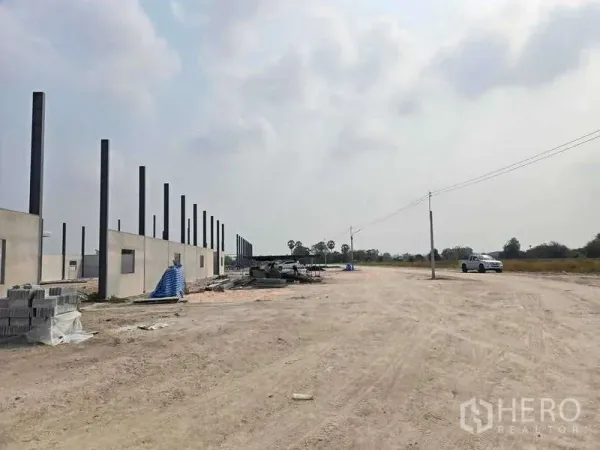 货栈 出售在Ban Bueng, Chon Buri - 仓库工地旁宽阔的碎石场地与出入口，道路有电线杆，周边开阔的田野。