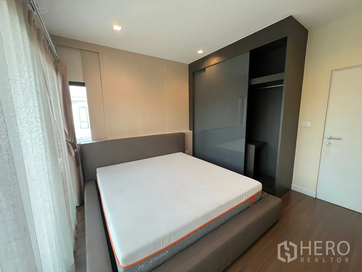 บ้าน ให้เช่าในBang Phli, Samut Prakan - ห้องนอนพร้อมตู้เสื้อผ้าบิวท์อินสีเข้ม เตียงยกพื้น และหน้าต่างมุมพร้อมผ้าม่าน