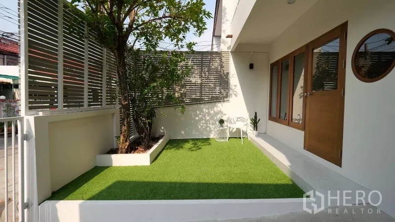 联排别墅 出租在Khlong Toei, Bangkok - 带人造草坪的前院，私密百叶围挡与木门通向屋内。
