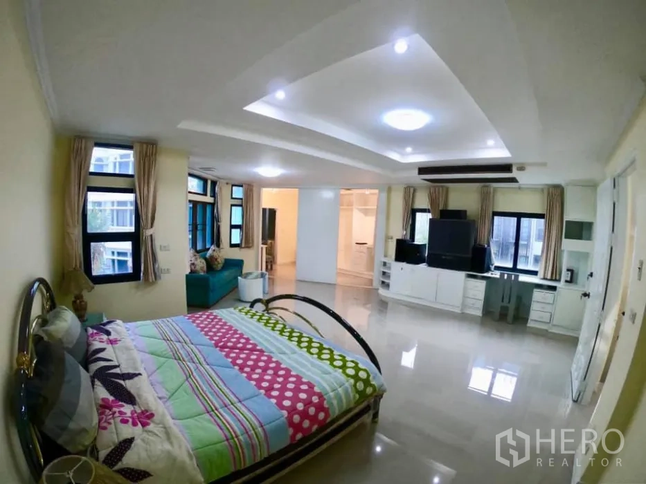 联排别墅 出租在Watthana, Bangkok - 宽敞卧室，含休闲区、电视墙柜、筒灯与多扇窗。