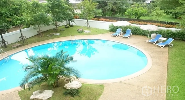 Apartment for rent in Khlong Toei, Bangkok - Aerial view of round swimming pool surrounded by trees, sun loungers and landscaped garden