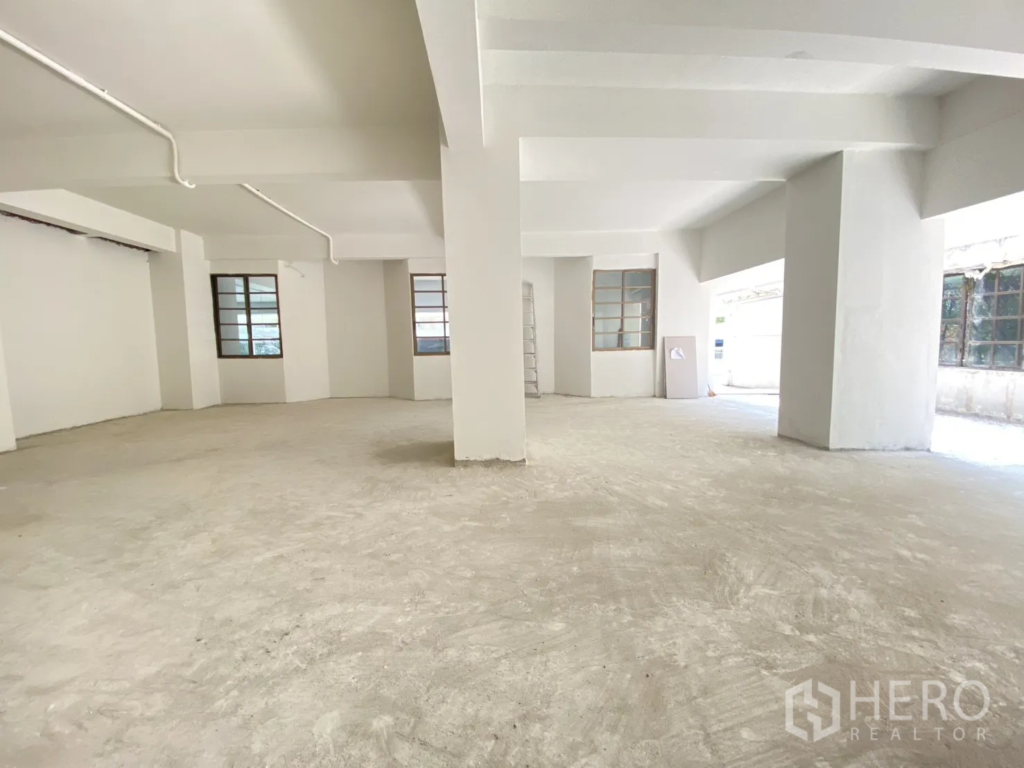 พื้นที่ขายปลีก for rent in Watthana, Bangkok - มุมห้องติดหน้าต่างหลายบาน เสาขาว และพื้นคอนกรีตดิบ.