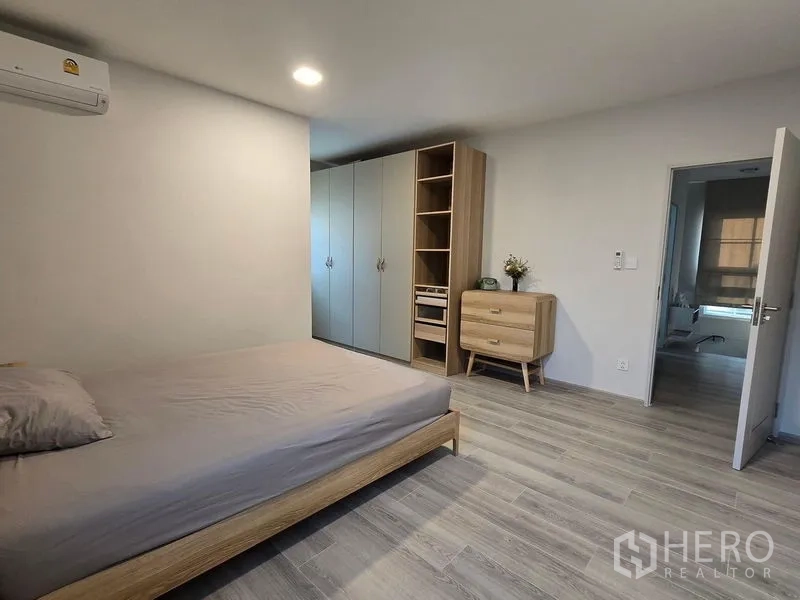 Detached House for rent in Bang Phli, Samut Prakan - Bedroom with large wardrobes, chest of drawers and grey wood flooring.